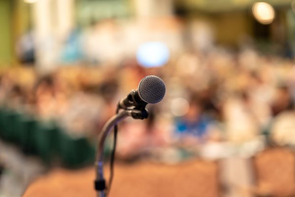 Microphone over the Abstract blurred photo of conference hall or seminar room with audience